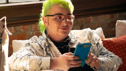 A genderqueer person looking at their phone